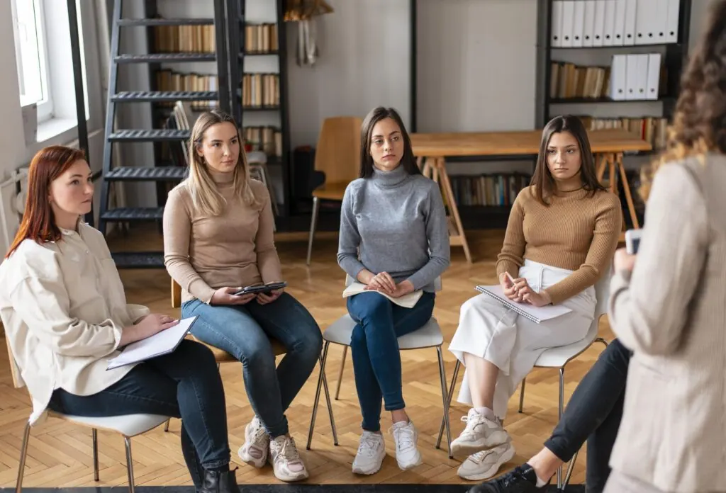 Grupo de mujeres participando en una sesión de terapia con una psicóloga